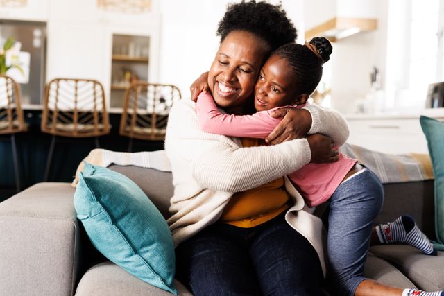Happy african american granddaughter hugging her smiling grandmother on couch at home - Download Free Stock Photos Pikwizard.com