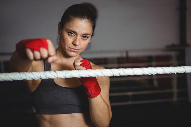 Portrait of confident female boxer performing boxing stance in fitness studio