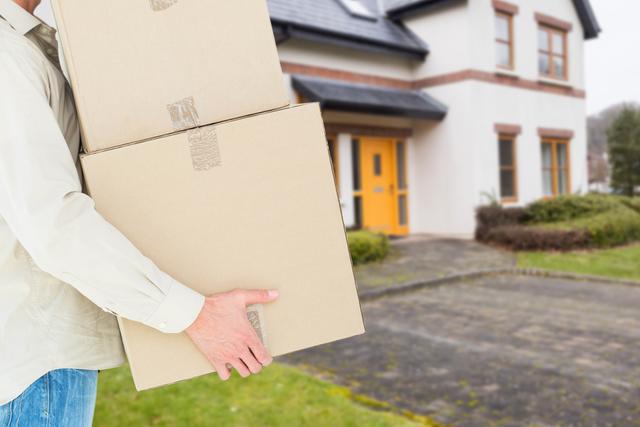 Digital composite of Midsection of man carrying boxes against house