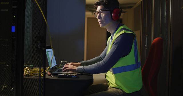 Asian male it technician wearing headphones and using torch checking computer server. information technology, data processing and computer servers.
