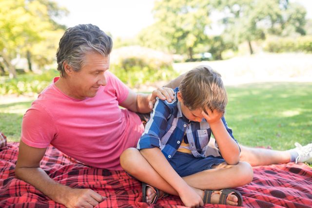 Father consoling his son at picnic in park - Download Free Stock Photos Pikwizard.com