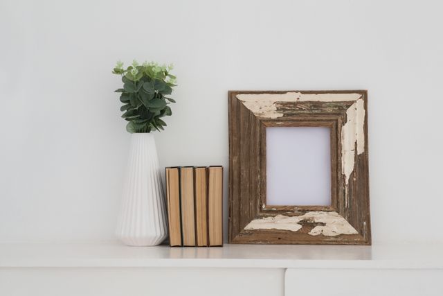 Wooden frame, vase and books arranged on table - Download Free Stock Photos Pikwizard.com