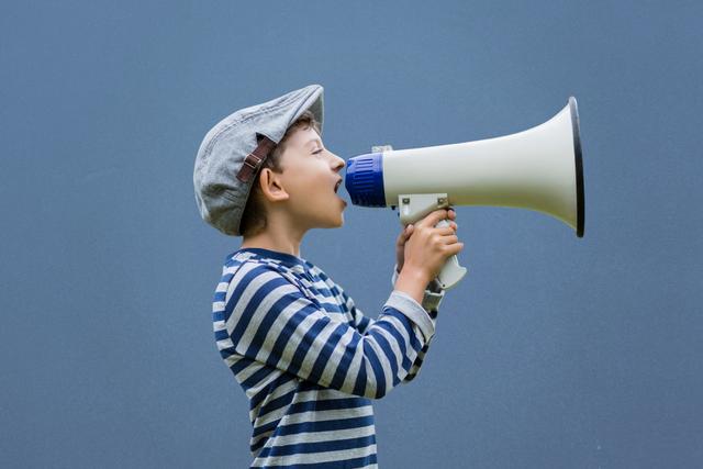 Side view of boy shouting on megaphone against blue background - Download Free Stock Photos Pikwizard.com