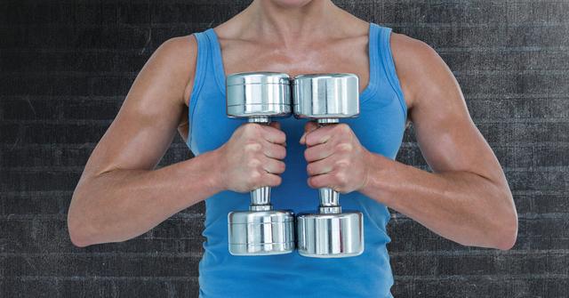 Close-up of a fit woman exercising with dumbbells