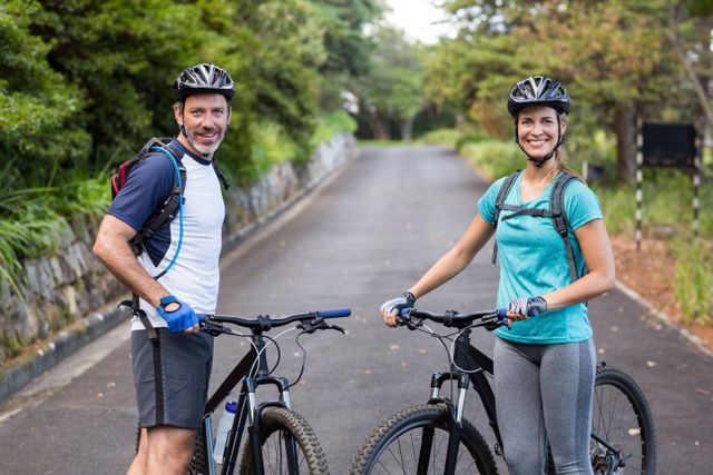 Athletic couple standing with mountain bike on the open road - Download Free Stock Photos Pikwizard.com