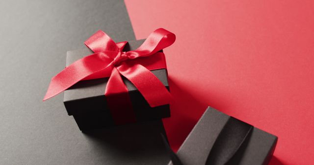 Close up of two black gift boxes with red and black ribbons on black and red with copy space - Download Free Stock Photos Pikwizard.com