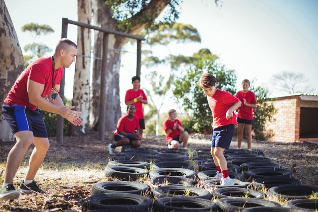Trainer instructing kids during tyres obstacle course training - Download Free Stock Photos Pikwizard.com