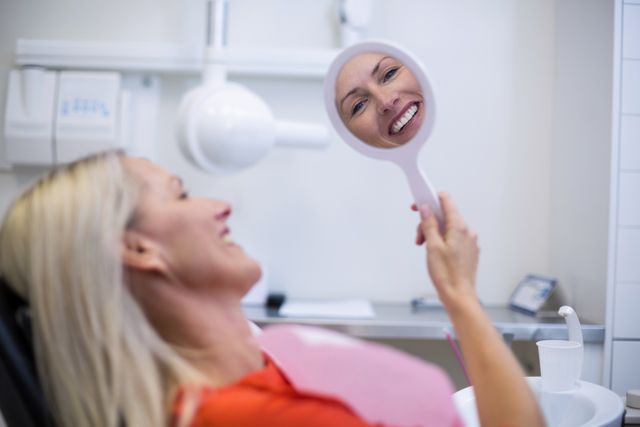 Patient checking her teeth in mirror - Download Free Stock Photos Pikwizard.com