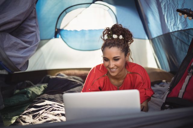 Happy young woman using laptop in tent - Download Free Stock Photos Pikwizard.com