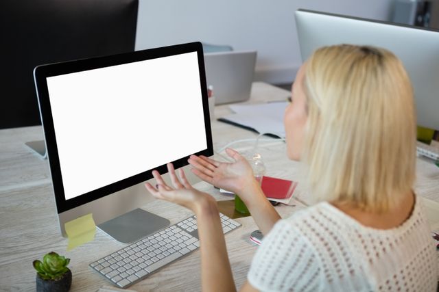 Young woman gesturing while working at desk in creative office