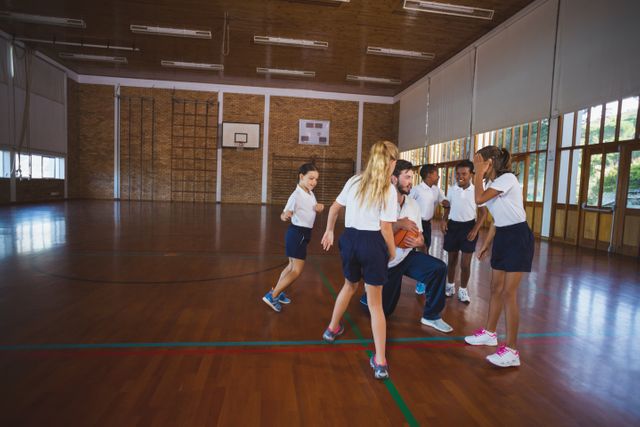 Sports teacher and school kids playing basketball - Download Free Stock Photos Pikwizard.com