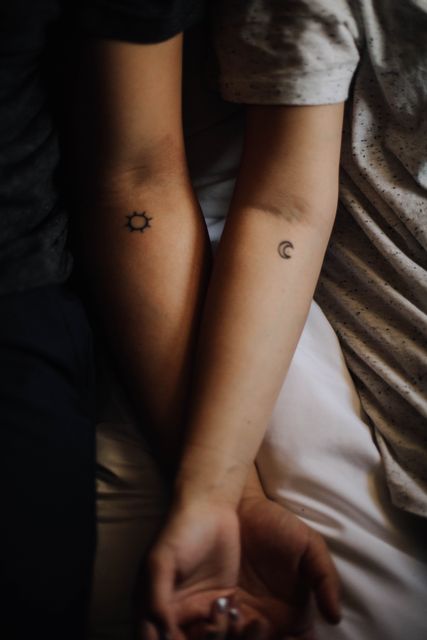 Close up view of couple with sun and moon tattoo on their forehands. love and relationship concept