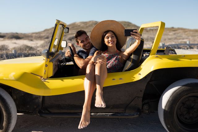 Happy caucasian couple sitting in beach buggy at sunny beach smiling and taking selfie - Download Free Stock Photos Pikwizard.com