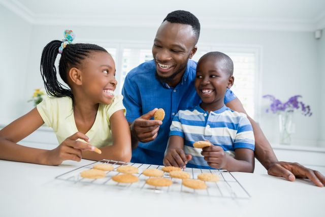 Smiling father and kids eating cookies at home - Download Free Stock Photos Pikwizard.com