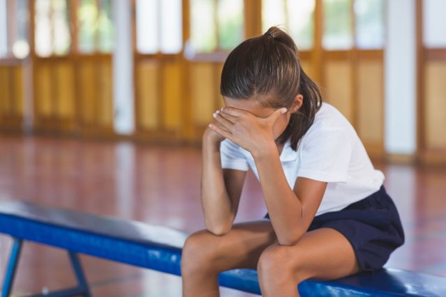 Sad schoolgirl sitting alone in basketball court - Download Free Stock Photos Pikwizard.com