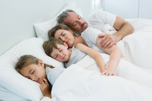 Family sleeping together in bed at home