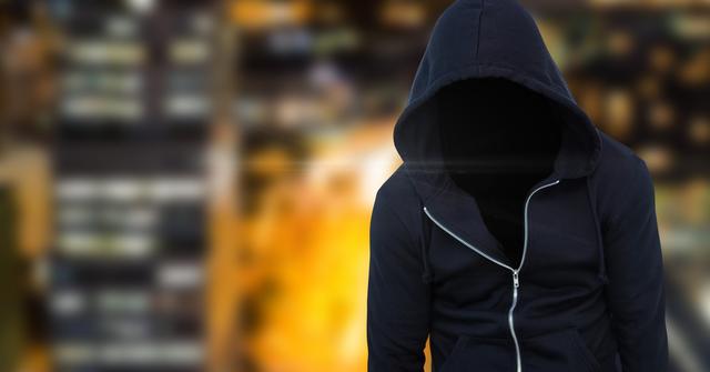 Anonymous criminal man wearing hood in front of city lights - Download Free Stock Photos Pikwizard.com