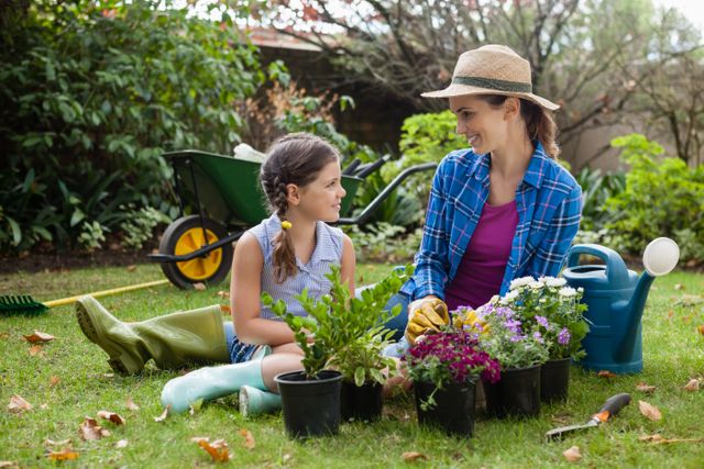 Smiling mother and daughter sitting with various potted plants - Download Free Stock Photos Pikwizard.com