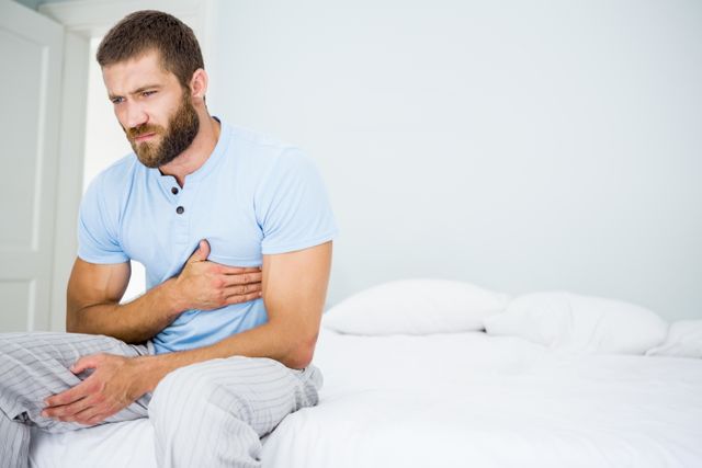 Young man having chest pain on bed - Download Free Stock Photos Pikwizard.com
