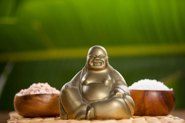Laughing buddha figurine and sea salt in wooden bowl - Download Free Stock Photos Pikwizard.com