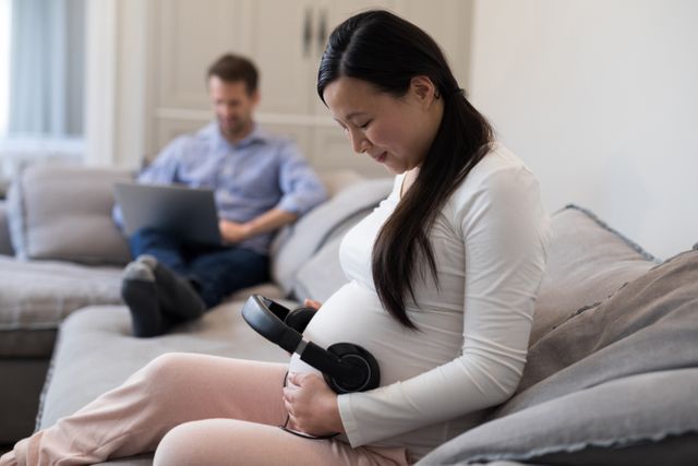 Pregnant woman placing headphones on her stomach - Download Free Stock Photos Pikwizard.com