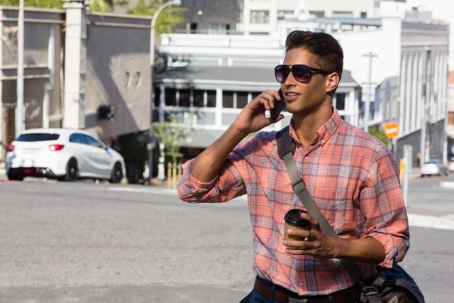 Young man in sunglasses talking on mobile phone on city street - Download Free Stock Photos Pikwizard.com