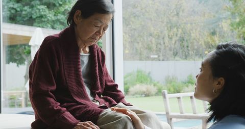 Smiling asian female physiotherapist treating knee of senior female patient and talking at surgery. physiotherapy, health and healthcare services.