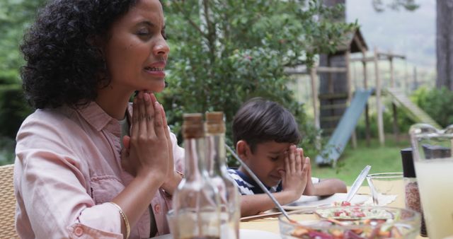 Biracial mother and son praying at table with meal in garden - Download Free Stock Photos Pikwizard.com