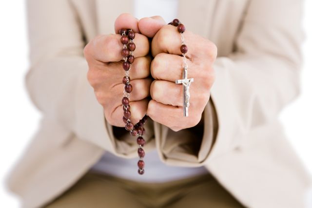 Midsection of woman holding rosary beads 