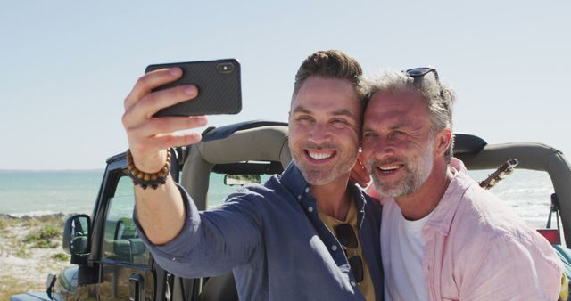Happy caucasian gay male couple taking selfies and smiling by car on sunny day at the beach - Download Free Stock Photos Pikwizard.com