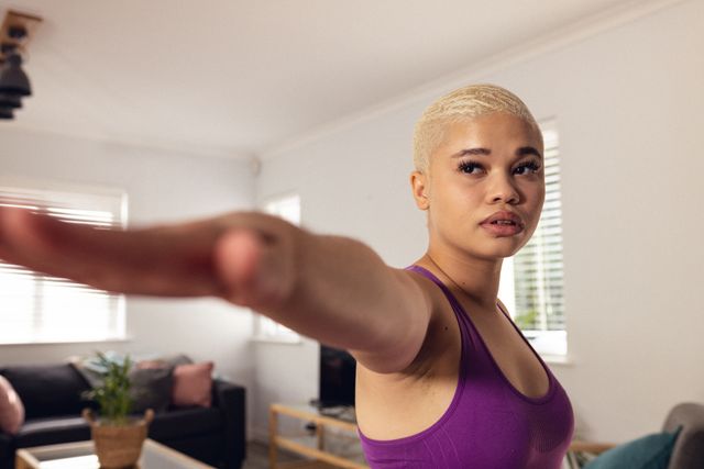 Biracial young woman with short hair stretching arm and exercising against wall at home, copy space - Download Free Stock Photos Pikwizard.com