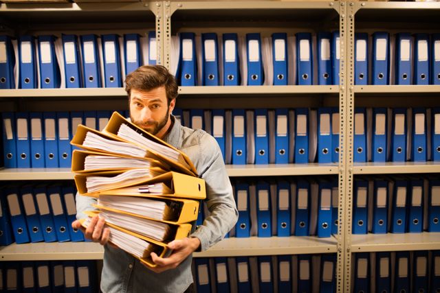 Businessman holding stack of files in storage room - Download Free Stock Photos Pikwizard.com