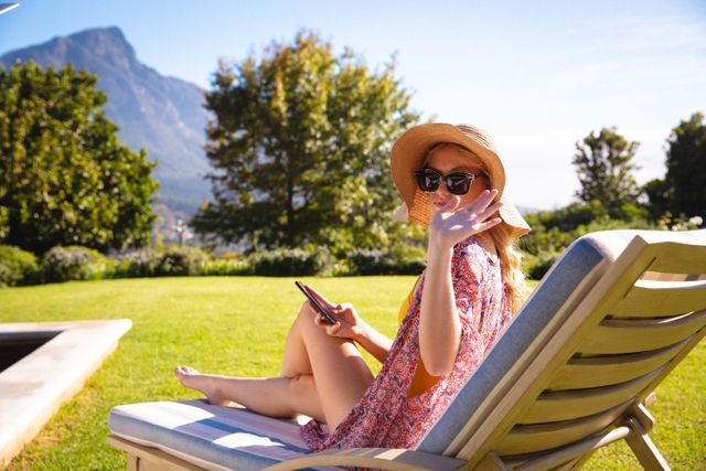 Happy caucasian woman wearing sunglasses, sitting on sunbed, using smartphone, relaxing - Download Free Stock Photos Pikwizard.com