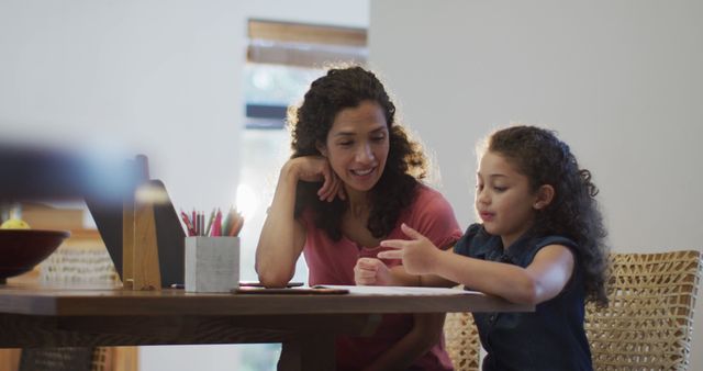 Happy mixed race mother and daughter doing homework together at home. domestic life and family leisure time concept.