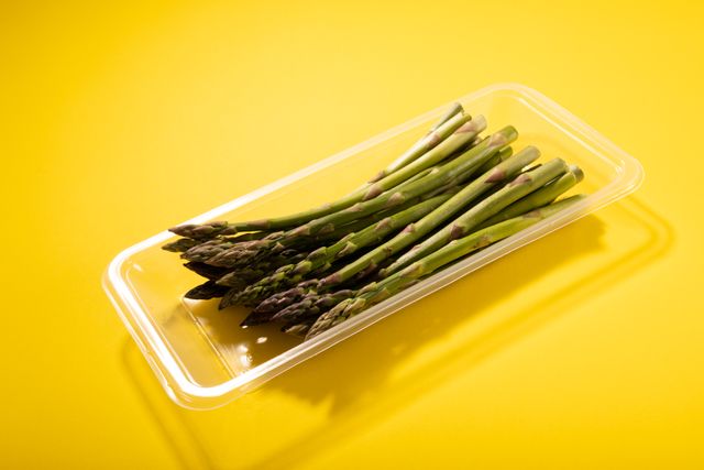 Close-up of asparagus in container on yellow background, copy space - Download Free Stock Photos Pikwizard.com
