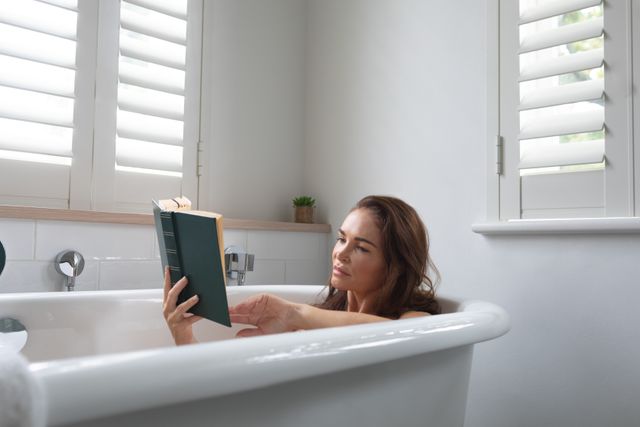 Woman reading a book while relaxing in bathtub at bathroom  - Download Free Stock Photos Pikwizard.com