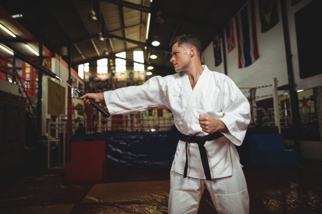 Karate player practicing with nunchaku in fitness studio
