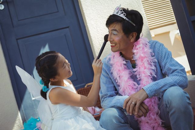 Cute daughter in fairy costume putting makeup on her fathers face - Download Free Stock Photos Pikwizard.com