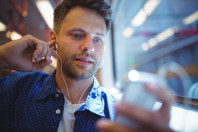 Handsome man listening music on mobile phone in train