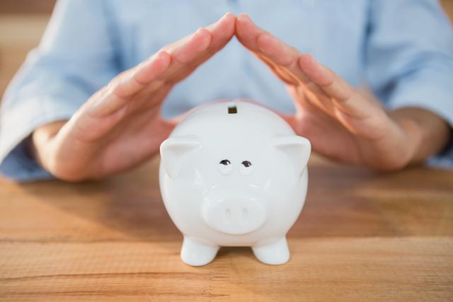 Man making a roof gesture on piggy bank - Download Free Stock Photos Pikwizard.com