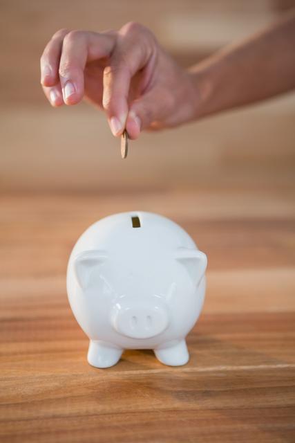 Hand inserting coin in piggy bank - Download Free Stock Photos Pikwizard.com