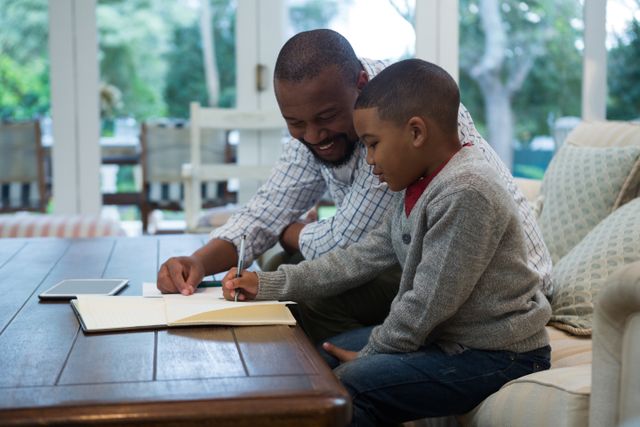Father helping his son with homework in living room - Download Free Stock Photos Pikwizard.com