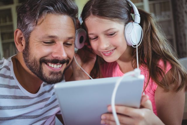 Father and daughter listening music on digital tablet at home