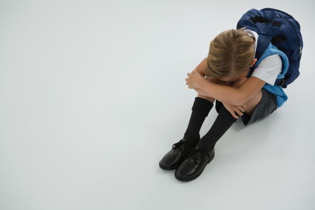 Sad schoolboy sitting on white background - Download Free Stock Photos Pikwizard.com