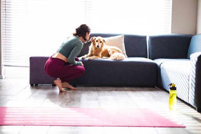 Caucasian woman scratching dog during exercise break in living room - Download Free Stock Photos Pikwizard.com