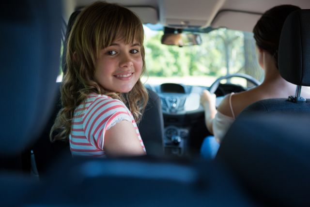 Teenage girl sitting in the back seat while woman driving a car - Download Free Stock Photos Pikwizard.com
