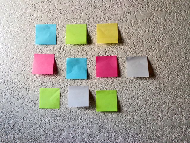 Multiple blank memo notes stuck on the textured wall. office and business concept