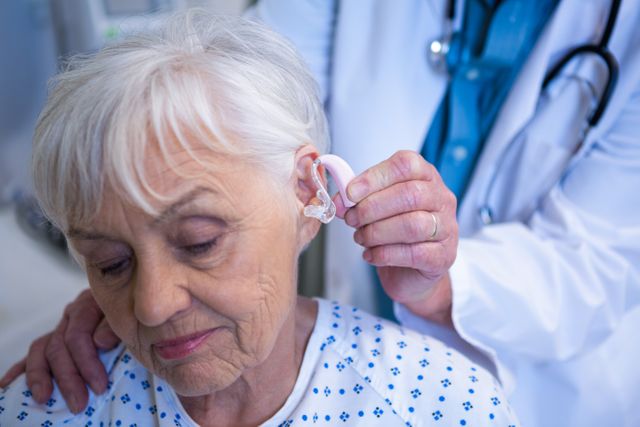 Doctor inserting hearing aid in senior patient ear - Download Free Stock Photos Pikwizard.com