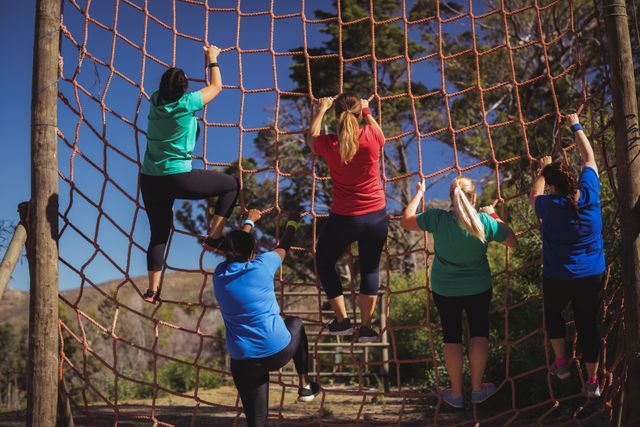 Group of fit woman climbing a net during obstacle course training in the boot camp