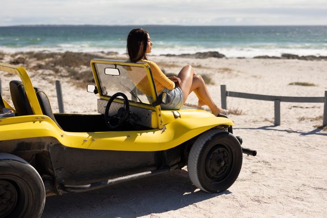 Caucasian woman sitting on beach buggy admiring the view on sunny beach by the sea - Download Free Stock Photos Pikwizard.com